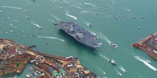 photo of Britain's £3 billion aircraft carrier just sailed back into port surrounded by a huge fleet of boats image
